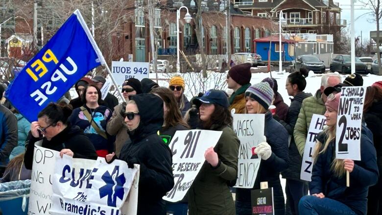 People holding signs calling for a fair wage at Confederation Landing Park in Charlottetown on Saturday.