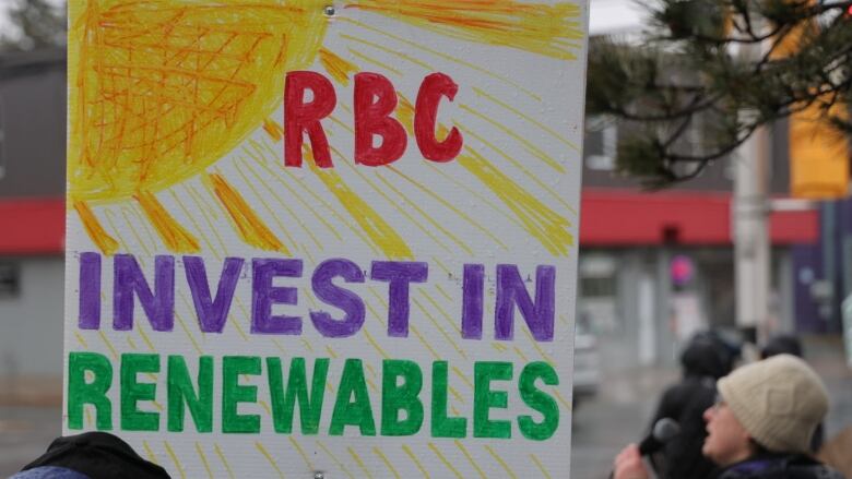 A protest sign says 'RBC invest in renewables'