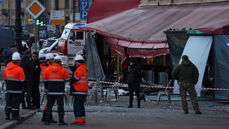 Investigators and members of emergency services work at the site of an explosion in a cafe.