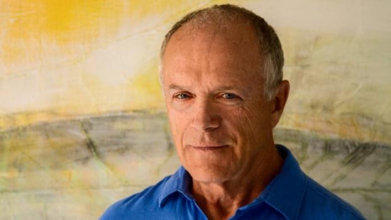 Portrait of a man with very short grey hair and wearing a blue polo shirt