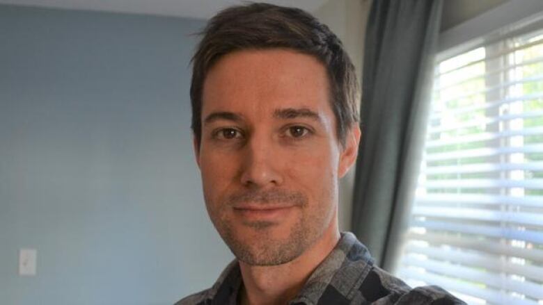 Close up portrait of a man with short hair wearing a plaid shirt