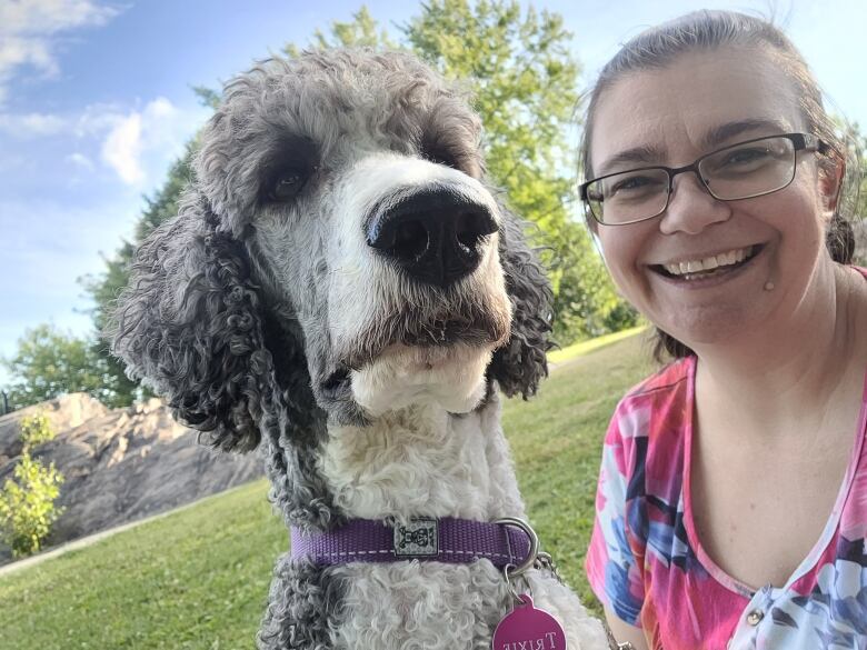 Trixie, a grey and white poodle next to Lesley-Anne Bardeggia at a park.