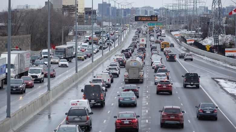 Traffic on a multi-lane divided highway with dirty snow piles off to the side.