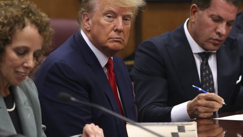 Trump seated between two lawyers.