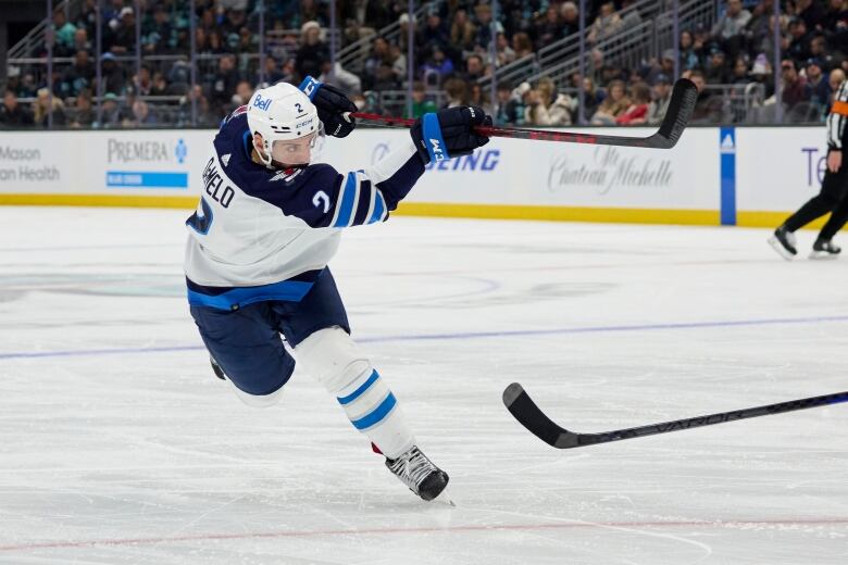 A hockey player in a blue and white jersey takes a shot.