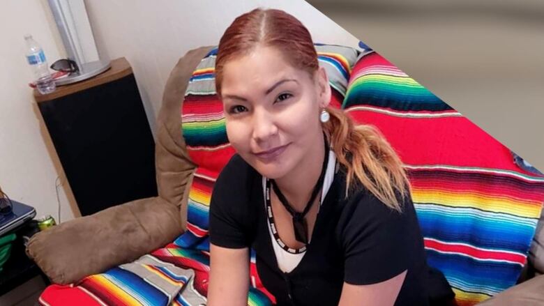 A woman in a black t-shirt sits on a rainbow-coloured blanket draped over a brown couch.