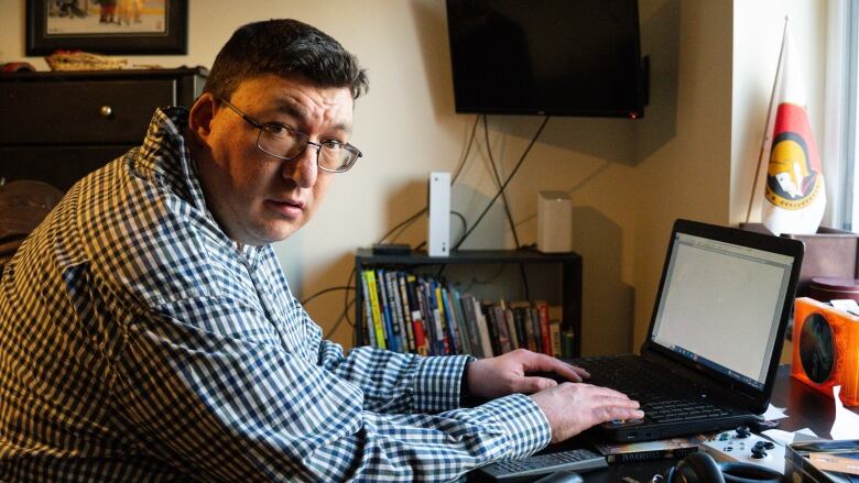 A man sits with his hands on a laptop keyboard.