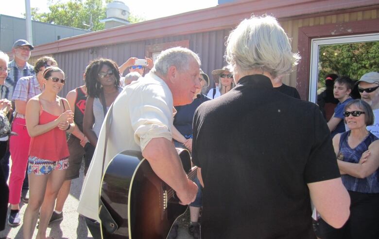 A man plays guitar in front of a crowd.