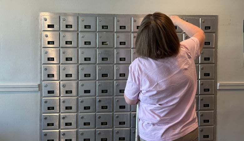 A woman checks her indoor mailbox.