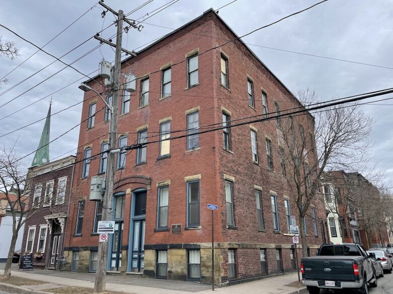 A brick apartment building with trucks and cars parked on the right side of it