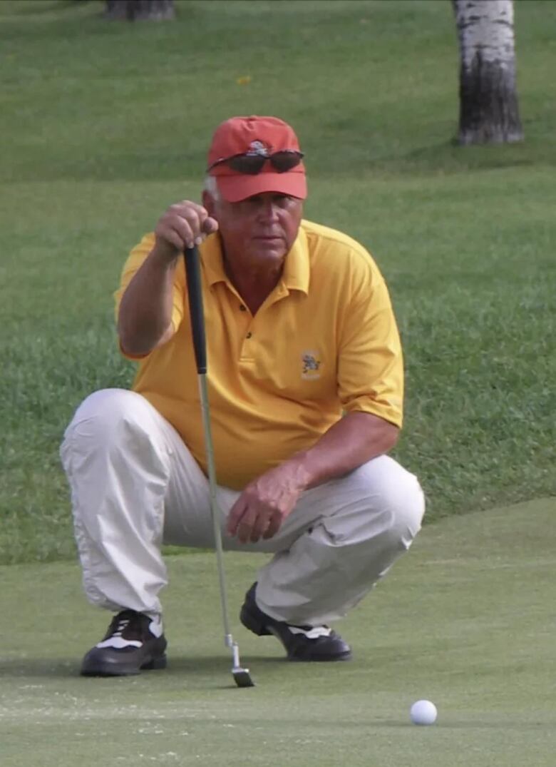 A man holding a putter on a green.