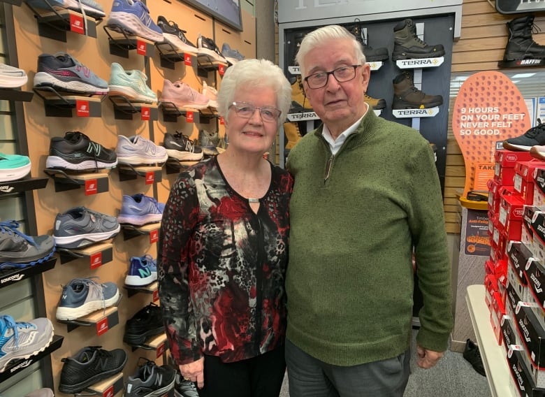 Old man and woman standing side-by-side inside a shoestore.