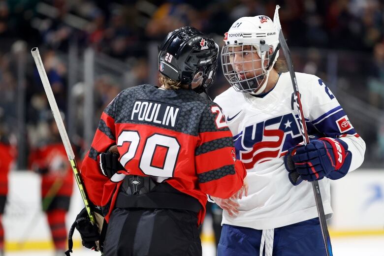 Two women hockey players shake hands at centre ice.