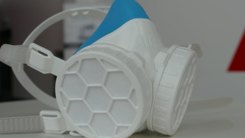 White and blue respirator mask with round covers on it.