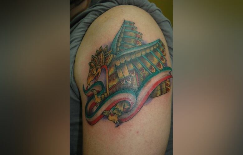 A large tattoo of a multicoloured dragon on an arm. 