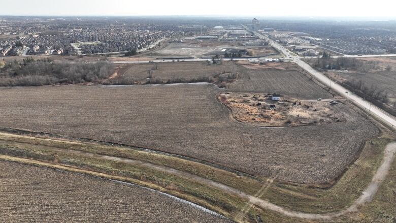 A drone photo of vacant land at the edge of a suburban housing development. 