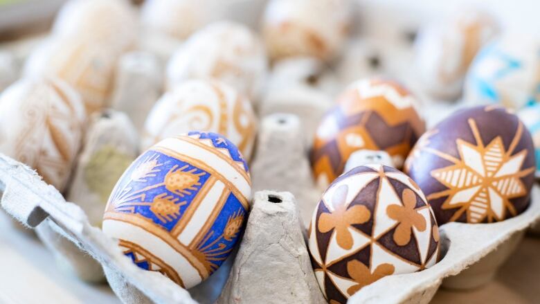 Coloured easter eggs sit in an egg carton.