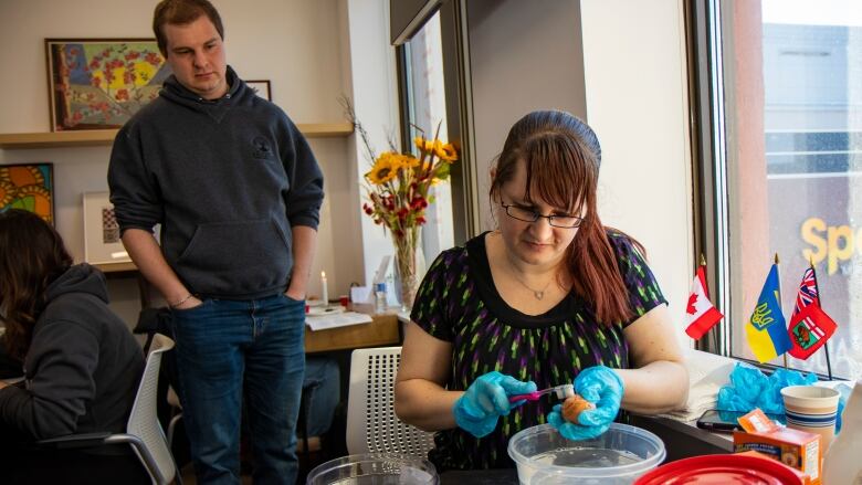 A woman uses a toothbrush to clean off a Ukrainian style easter egg.