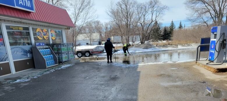 Staff pump water from a flooded gas station parking lot