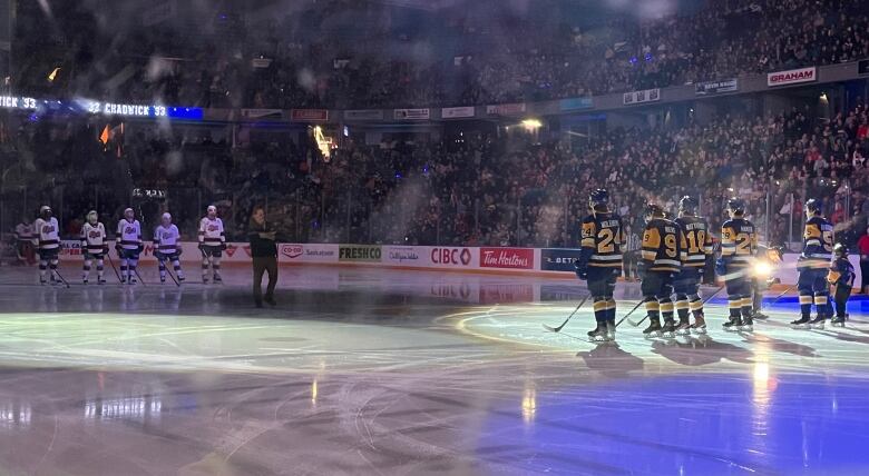 Ten ice hockey players stand on their respective blue lines before the hockey game begins