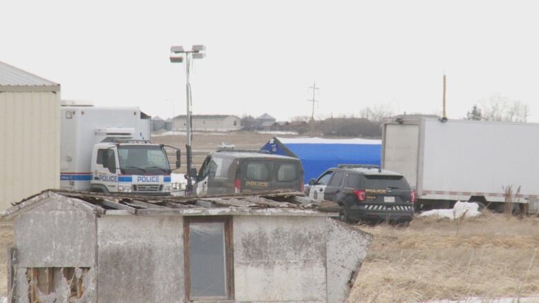 Multiple police vehicles and a blue tent are pictured.