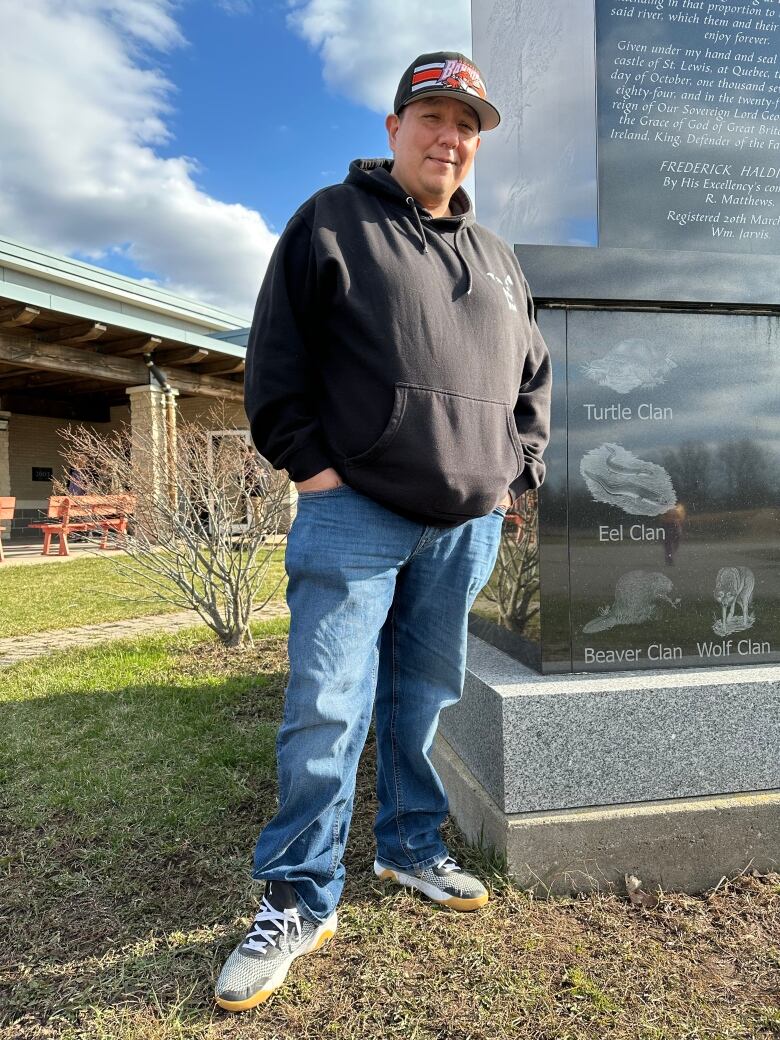 Man poses by monument, smiling, hands in pockets.