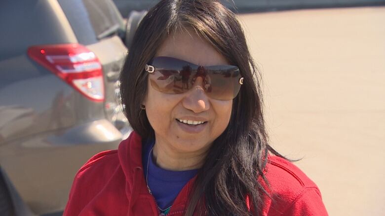 A lady with sunglasses and a red sweater.