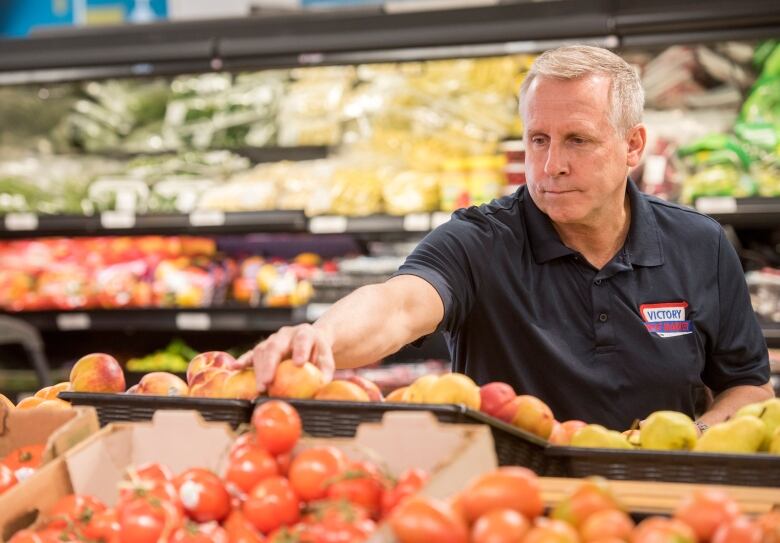 Alex Scholten, manager of Victory Meat & Produce Market Ltd. in  Fredericton, arranges fresh produce on display at the store.