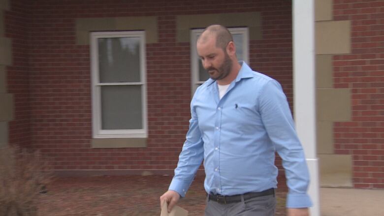 A man walks away from a brick building.