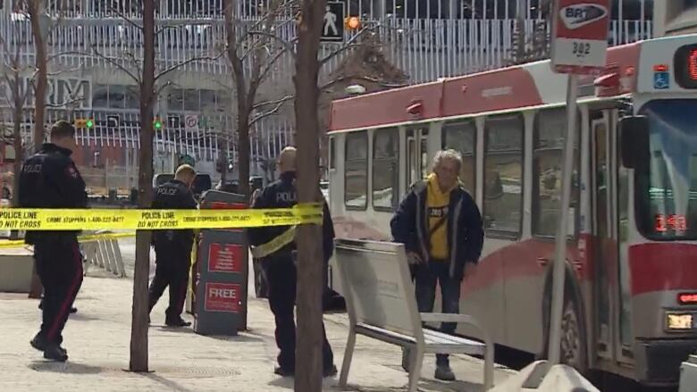 A man walks past a bus with police officers around