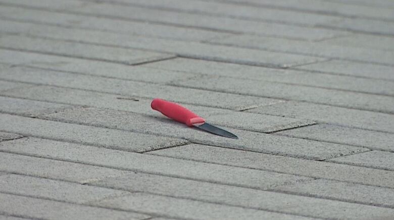 A knife is pictured on the sidewalk.