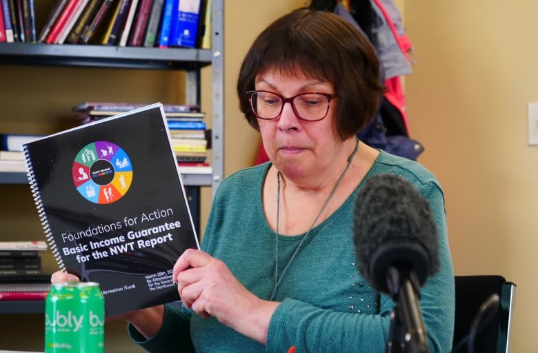 A woman stands holding a booklet.