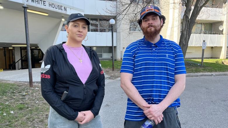 A man and a woman stand outside an apartment building.