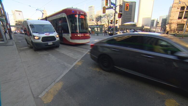 A road with a streetcar and cars.