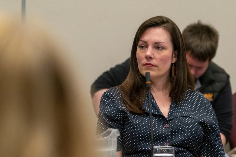 A woman in a black blouse sits at a table. 