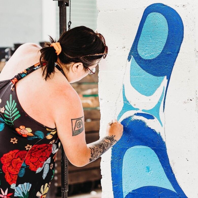 Artist paints a blue bird mural