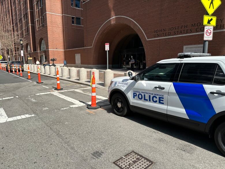 A police vehicle and barricades are shown outside a building.