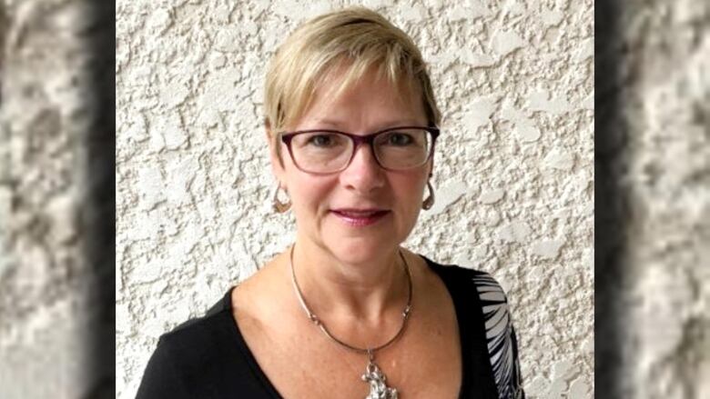 A headshot shows a woman with short blond hair wearing glasses.