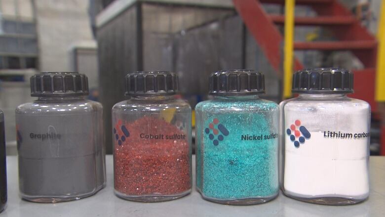 Four jars containing grains of colourful metals.