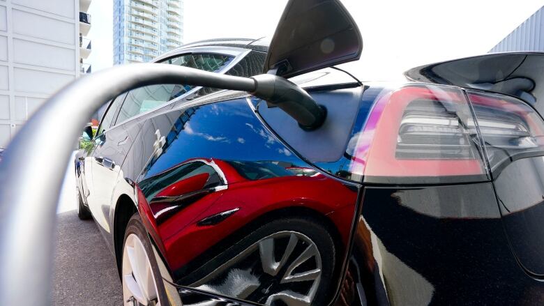 A black electric car charging.