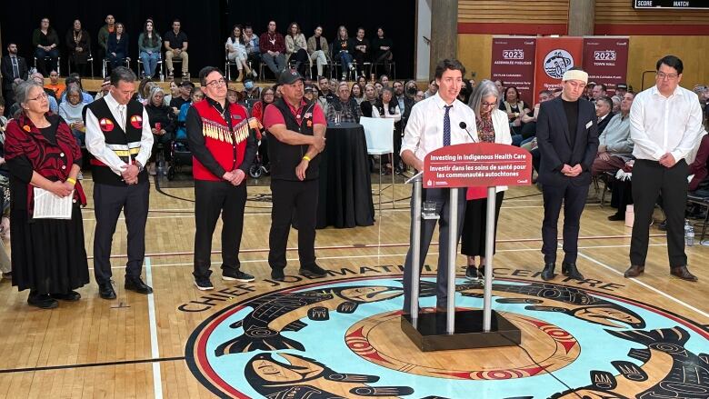 Just Trudeau stands with leaders from for First nation Health in B.C. in a packed gymnasium. 