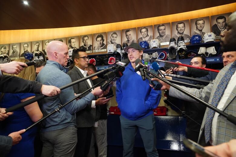 Man stands surrounded by microphones and reporters.