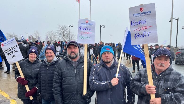 Five people face the camera holding protest signs.