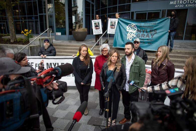 A family stands in front of reporters outside an office building.