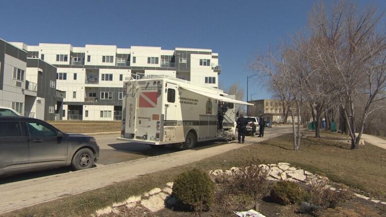 A police underwater search and identification unit truck is seen parked on a street next to a river path and condos.