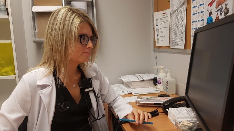 A doctor is sitting at a desk.