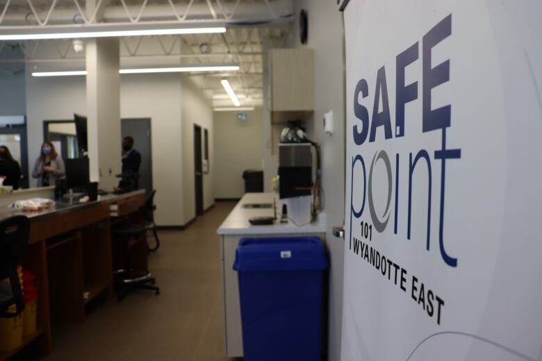 A banner reading SafePoint to the right with journalists inspecting the facility to its right