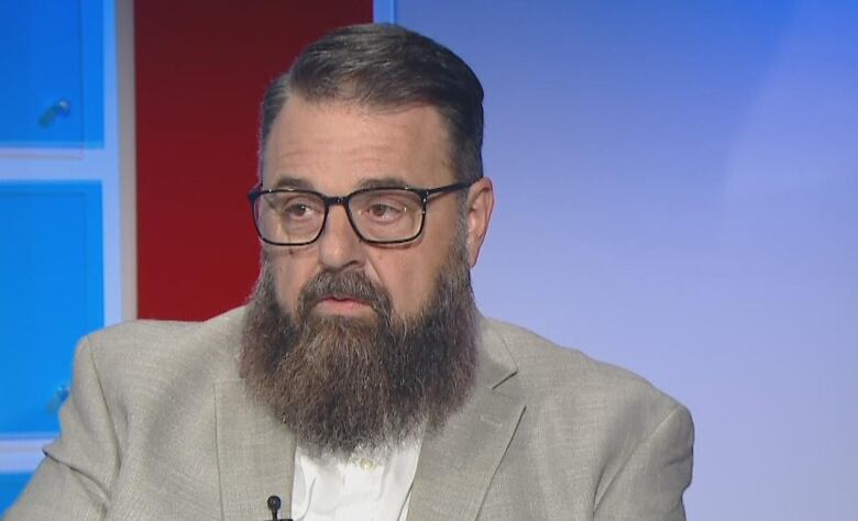 A bearded man sits in a television studio