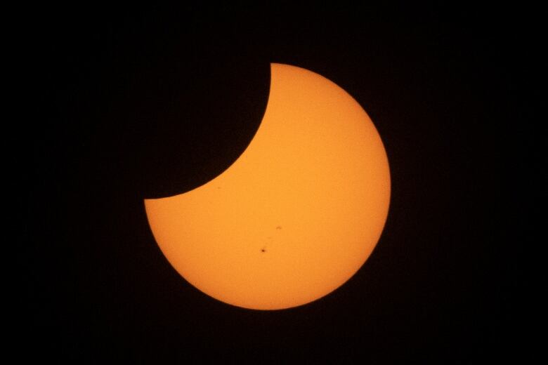 An orange moon is shown in a black sky.