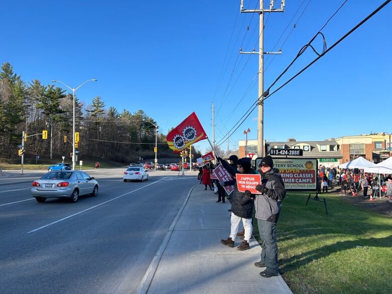 Striking workers on a suburban sidewalk on a sunny day.